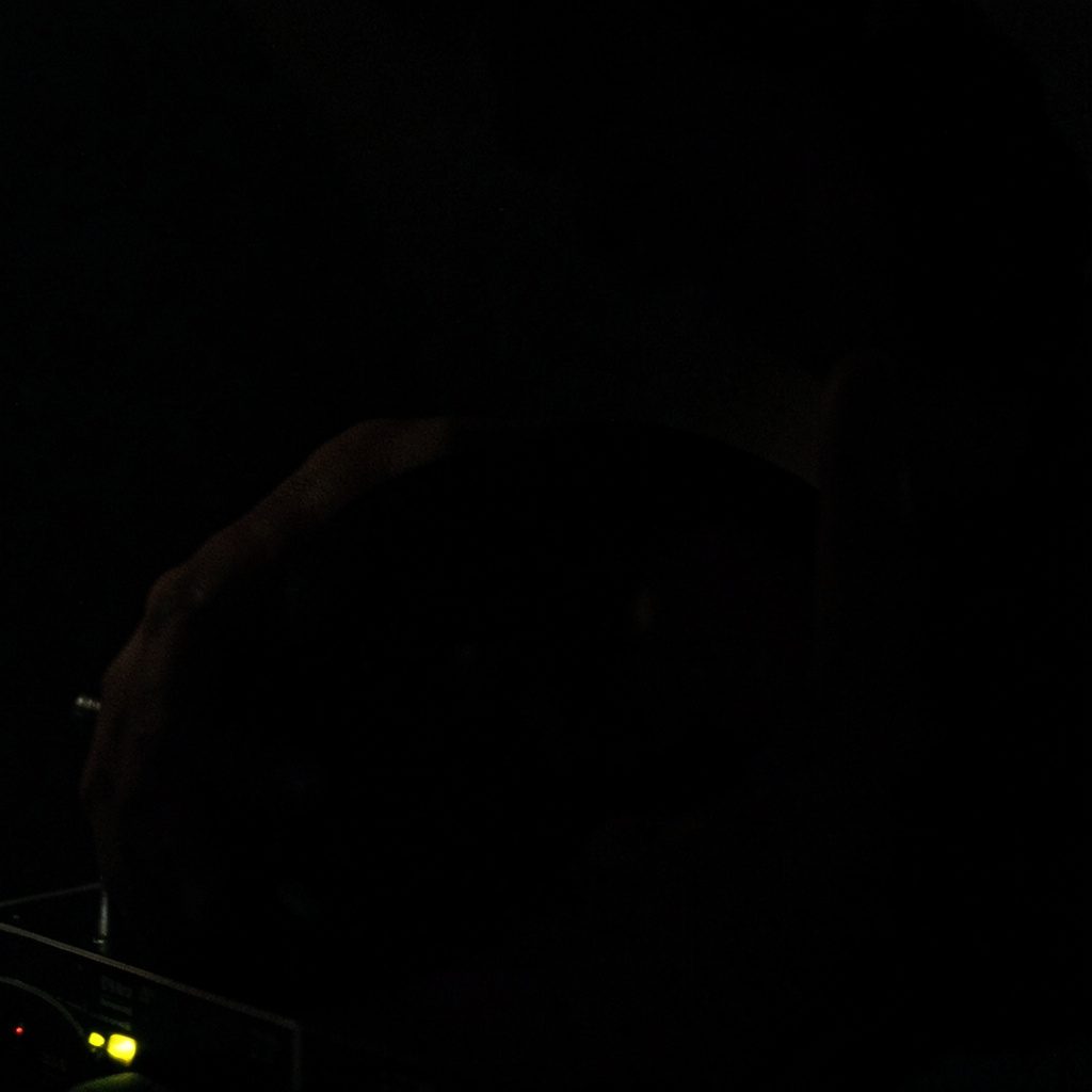 Dark close-up of a magnet near electronic circuitry, deep shadows with subtle metallic reflections.